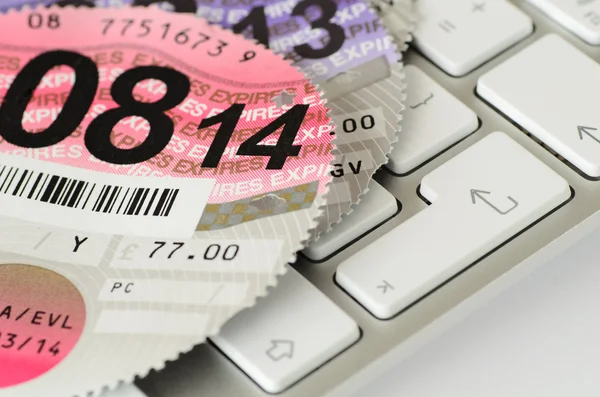 Expired UK vehicle tax disc on a keyboard.