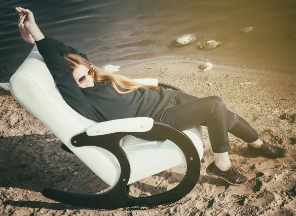 Beautiful happy woman relax in chair on lake morning