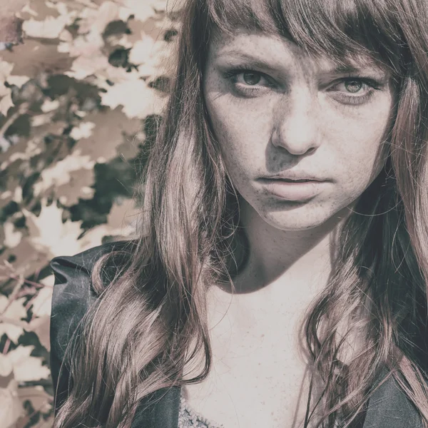 Beautiful woman with freckle and red hair in autumn park