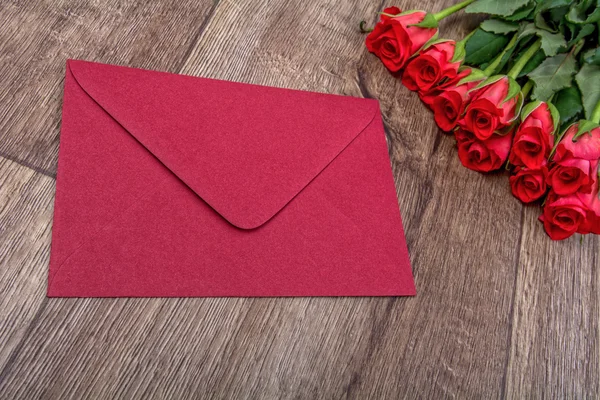 Red envelope and roses on a wooden background