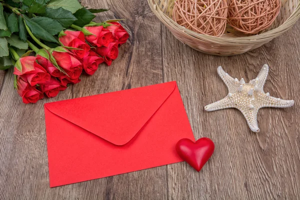 Red envelope, heart, starfish and roses on a wooden background