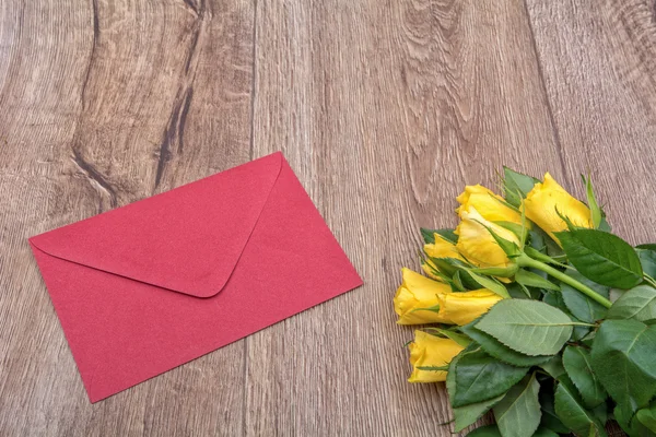 Red envelope and roses on a wooden background