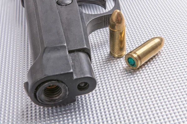 Bullets and gun on aluminium background