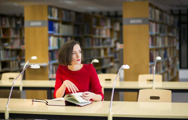 Woman in thought in library looking left