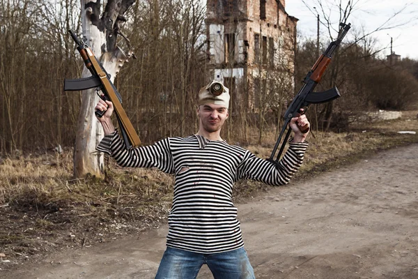 Dressed in sailor shirt man holds two guns in his hands