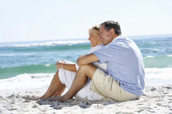 Senior Couple Sitting On Sandy Beach