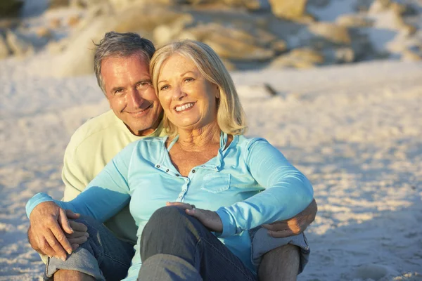Senior Couple Sitting On Sandy Beach