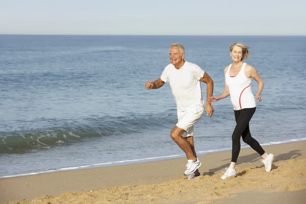 Senior Couple Jogging Along Beach