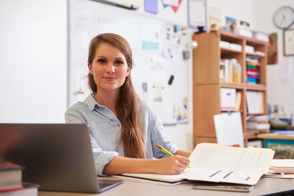 Young teacher at desk looking to camera