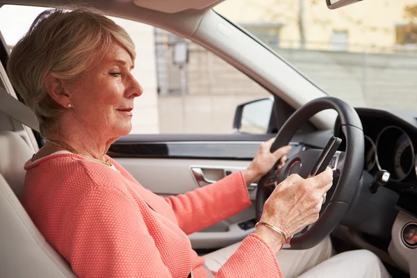 Senior female driver using smartphone