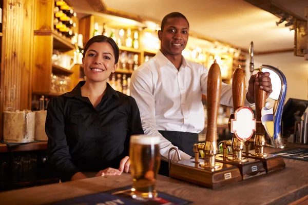 Man and woman working behind a bar