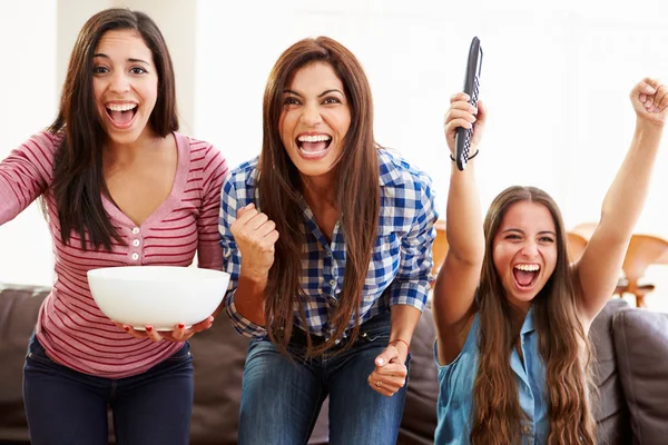 Group Of Women Sitting On Sofa Watching Sport Together