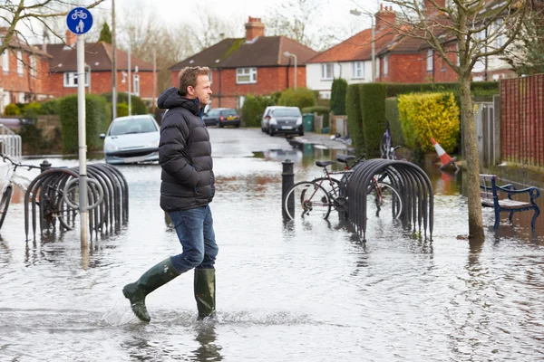 Man Walking Along Flooded Urban Street