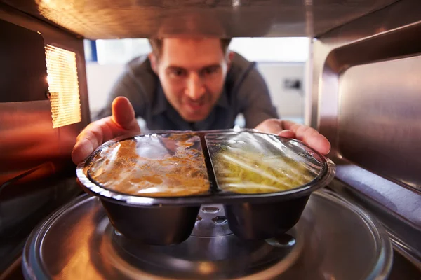Man Putting TV Dinner Into Microwave