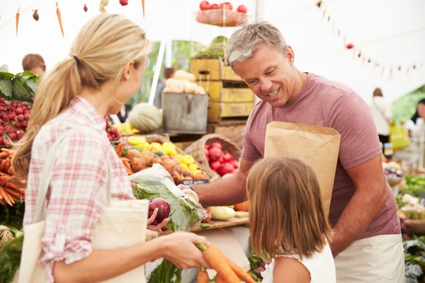 Family Buying Fresh Vegetables At Market