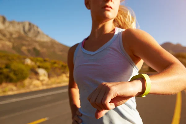 Woman running and checking her sports watch