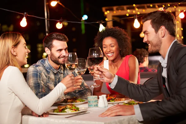 Friends eating dinner at rooftop restaurant