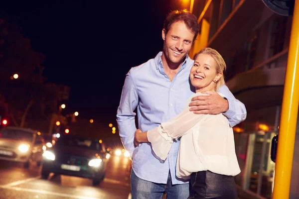 Couple embracing on street at night