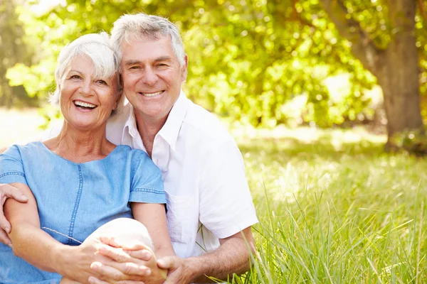 Senior couple sitting together on grass