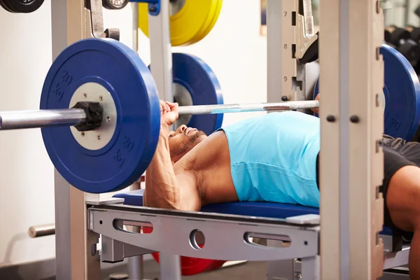 Man bench pressing weights at a gym