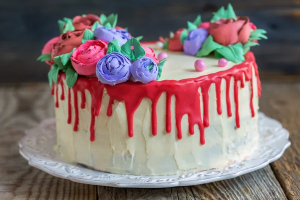Cake decorated with flowers from cream and red chocolate.