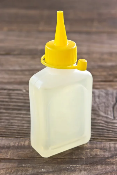 Bottle of lubricating machine oil on wooden background