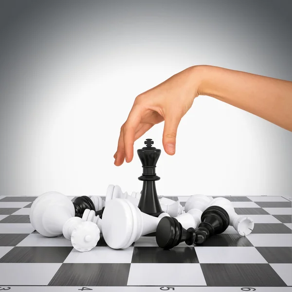 Woman hand touching king figure on chess board