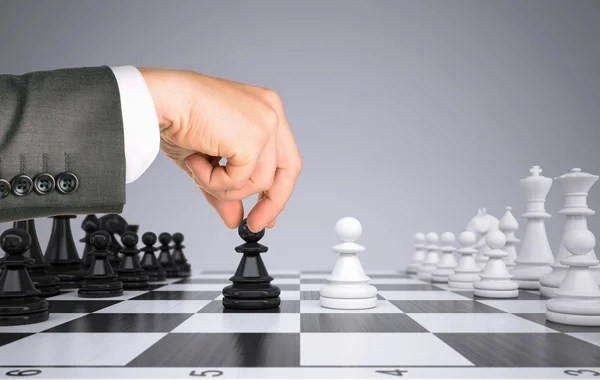 Businessman hand touching pawn figure on chess board