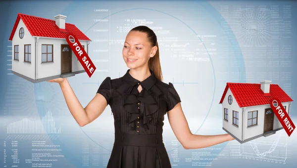 Businesswoman holding two house with tags for sale and rent