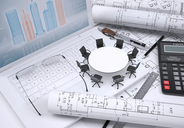 Round table, scrolled drawing, glasses, laptop, calculator and a few other tools, architectural drawings