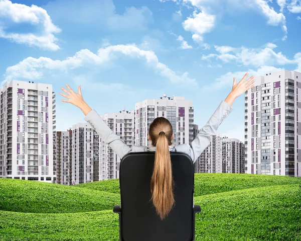 Businesswoman sitting on office chair. Green hills with buildings and sky