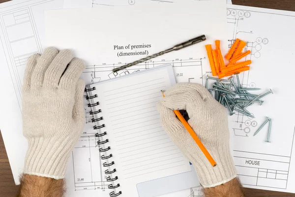 Man writing in pad with screws