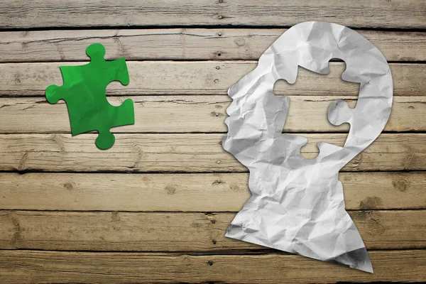 Paper humans head with green puzzle symbol