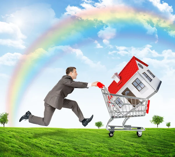 Running businessman with house in shopping cart