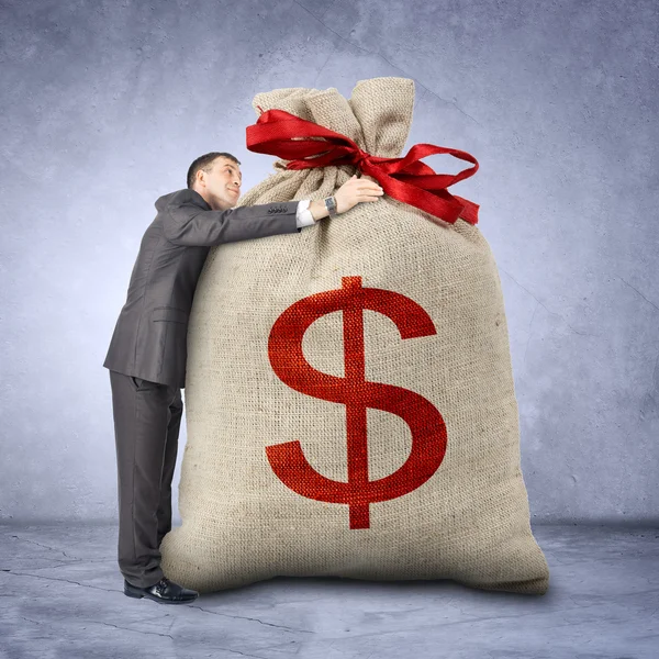 Businessman hugging bag with dollar sign