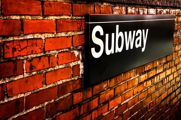 Subway sign on  red brick wall at night in Manhattan, New York