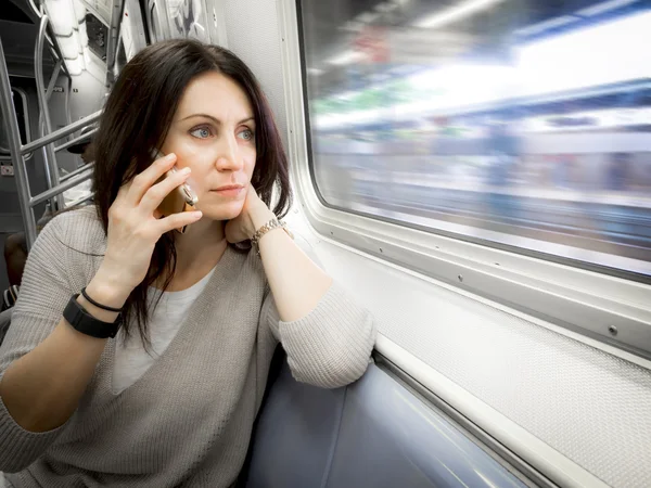 Woman in her 30s is riding the subway ans looking out the window