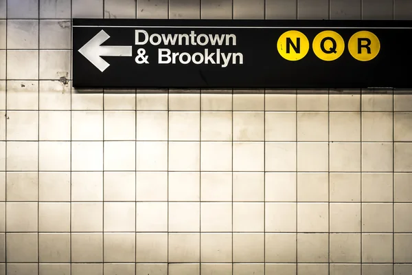 Subway sign in Manhattan directing passengers  and travelers to the downtown and Brooklyn trains