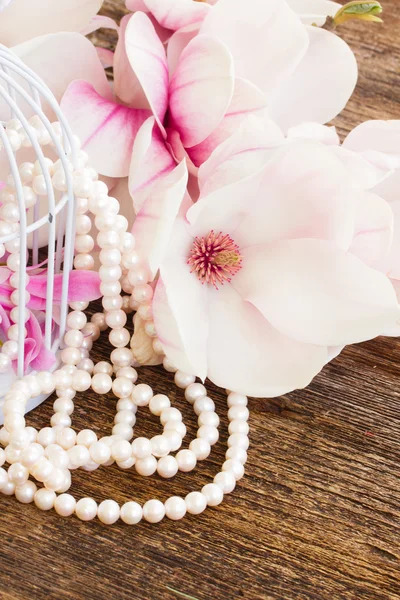 Magnolia flowers with pearls on wooden table
