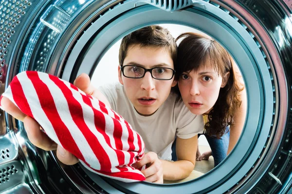 Funny couple loading clothes to washing machine