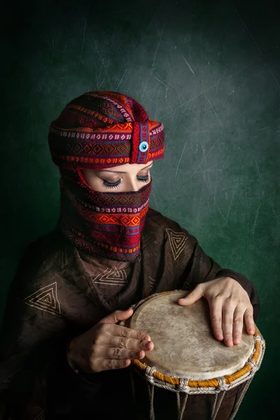 Woman in turban playing drum