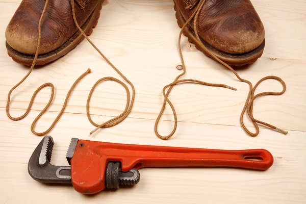 Old shoes with shoelaces with red adjustable wrench