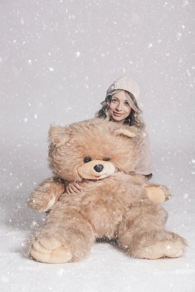 Casual smiling young woman in knitted clothes holding big soft t