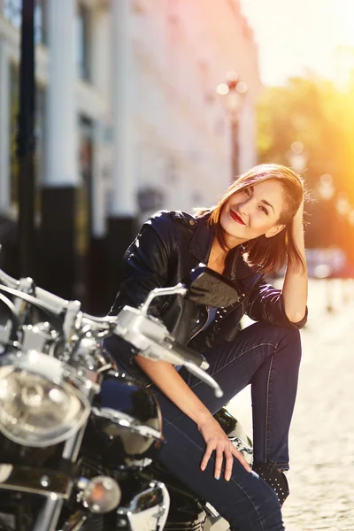 Biker girl in a leather jacket on a motorcycle