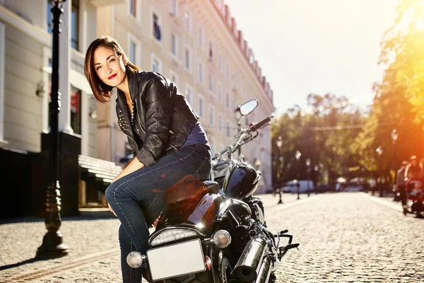 Biker girl in a leather jacket on a motorcycle
