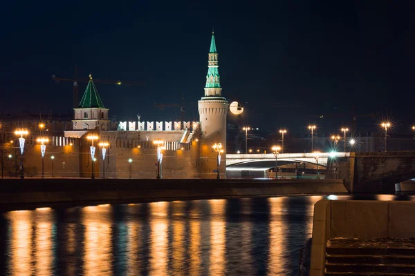 View to embankment of the river, Moscow Kremlin\'s wall and tower with full moon on background from another side of the river in the night