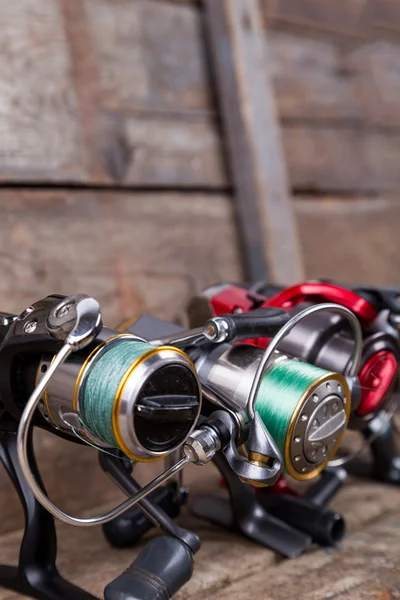 Different fishing reels with line on wooden background