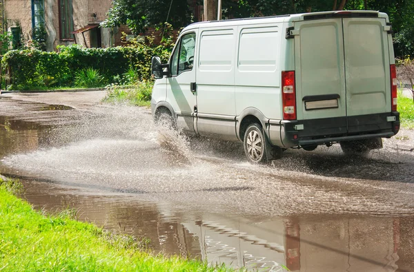 Commercial vehicle rides on big puddle on the road