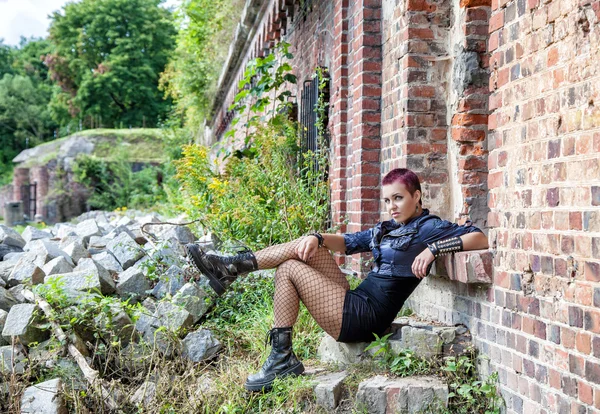 Punk girl sitting on the porch of an old castle