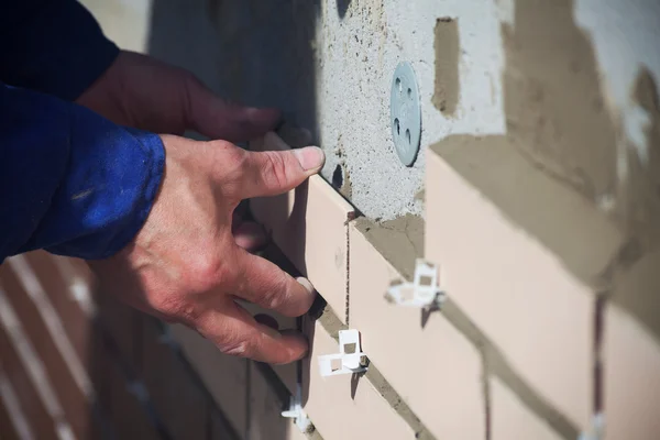 Worker puts the ceramic tiles on the wall